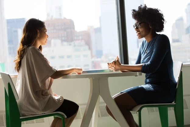 Two women having a conversation at a table about how to reduce technical debt.