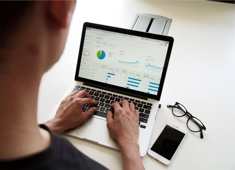 Cirrus Insight. Man reviews data on his Macbook laptop with glasses and phone on table.