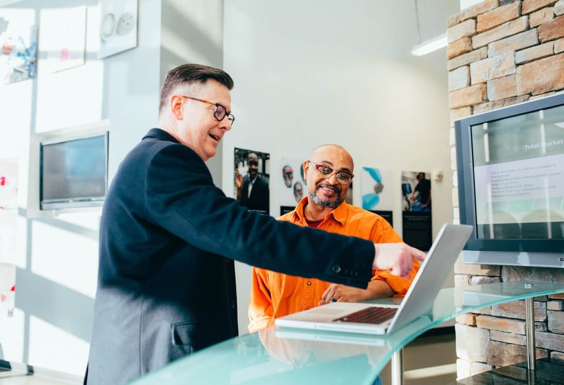 Cirrus Insight. Salesman works with client at desk, pointing at laptop.